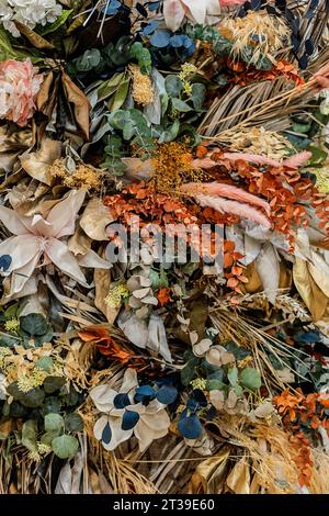 Ein lebhaftes und strukturiertes Arrangement aus getrockneten Blumen und Laub in verschiedenen Farbtönen. Stockfoto