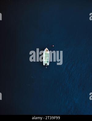 Blick von oben auf ein kleines Fischerboot mit Ausrüstung, die im dunkelblauen Meerwasser in El Rompido verankert ist Stockfoto