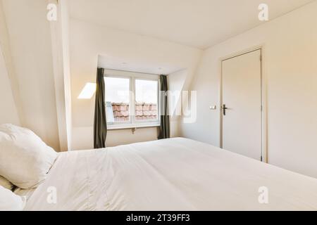 Inneneinrichtung des modernen Schlafzimmers mit komfortablem großem Bett und Fenster im Apartment mit weißen Wänden und Tür Stockfoto