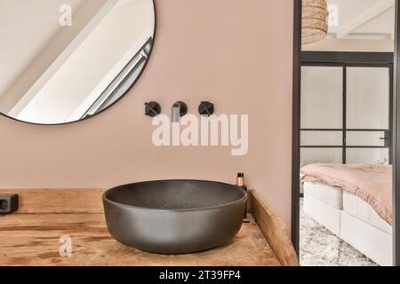 Spiegel an rosafarbenen Wänden mit schwarzem Waschbecken und Wasserhähnen im stilvollen Badezimmer in einem modernen Zuhause Stockfoto