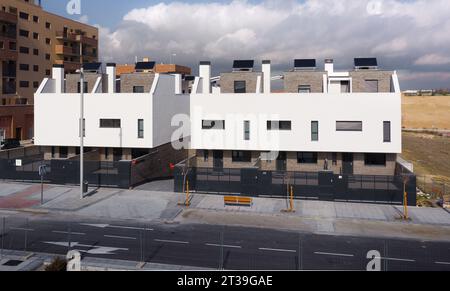 Von oben moderne Stadthäuser mit einer eleganten weißen Fassade, die einem Backsteingebäude gegenüberstehen, das sich in einem neu entwickelten Gebiet in Madrid, Spanien, darunter befindet Stockfoto