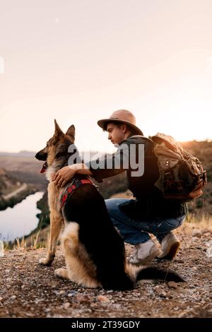 Seitenansicht eines freundlichen Deutschen Schäferhunds mit Mann, der während eines Spaziergangs in der Natur sitzt Stockfoto