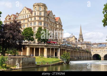 Das Empire Hotel (L), Pulteney Bridge & Weir, mit dem Turm der St. Michael's Church im Hintergrund. Bath, Somerset, England. Stockfoto