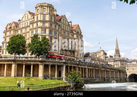 Das Empire Hotel (L), Pulteney Bridge & Weir, mit dem Turm der St. Michael's Church im Hintergrund. Bath, Somerset, England. Stockfoto