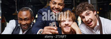 Banner fröhlicher multiethnischer Kollegen in formeller Kleidung, die nach der Arbeit Flaschen Bier in der Bar halten Stockfoto