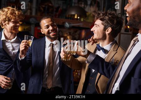 Junggesellenabschied, fröhliche Männer, die mit Gläsern Whiskey in der Bar tosten, Bräutigam und beste Männer Stockfoto