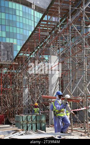 Ausländische Arbeiter aus Indien und Pakistan bauen Gerüste auf einer großen Baustelle in Abu Dhabi, VAE. Stockfoto