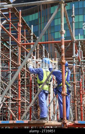 Ausländische Arbeiter aus Indien und Pakistan bauen Gerüste auf einer großen Baustelle in Abu Dhabi, VAE. Stockfoto