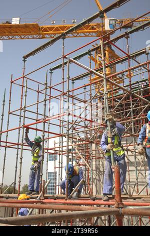 Ausländische Arbeiter aus Indien und Pakistan bauen Gerüste auf einer großen Baustelle in Abu Dhabi, VAE. Stockfoto