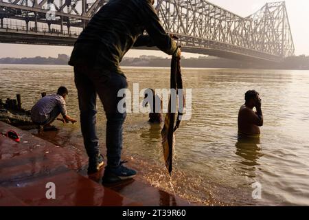 Kalkutta, Indien. Oktober 2023. Man sieht die Menschen, die am Morgen Pujas am Hootly River mit der Howrah Brücke im Hintergrund spielen. (Credit Image: © Davide Bonaldo/SOPA Images via ZUMA Press Wire) NUR REDAKTIONELLE VERWENDUNG! Nicht für kommerzielle ZWECKE! Stockfoto