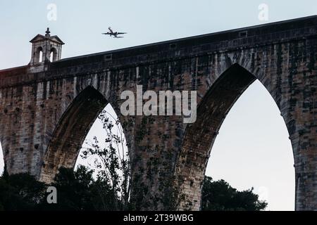 Lissabon, Portugal - 23. Oktober 2023: TAP Airlines Flugzeug fliegt über Aguas Livres Aquädukt mit Stadtbild auf einem Hintergrund, horizontale Ernte Stockfoto