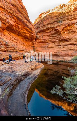 Die Menschen versammelten sich kontemplativ im Garden of Eden, einem ständigen Wasserloch am Kings Canyon (Watarrka) im Northern Territory von Australien Stockfoto