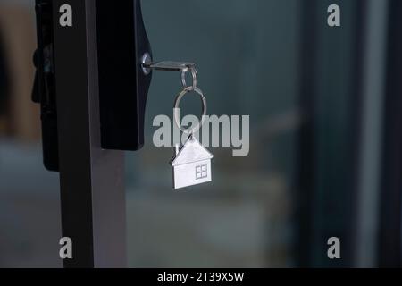 Schlüssel mit Schlüsselanhänger in häuslicher Form im Türschlüsselloch. Stockfoto