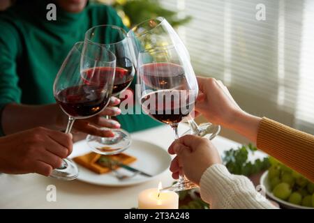 Gruppe von Freunden, die mit Gläsern roten Winters toasten und Weihnachten zu Hause feiern Stockfoto