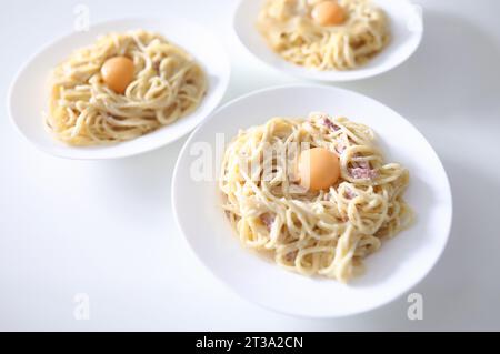 Auf dem Tisch sind drei Teller Spaghetti Carbonara mit pochiert Eigelb Stockfoto