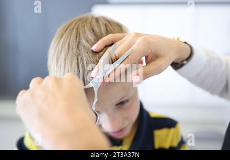 Master Friseur schneidet Pony des blonden Jungen. Stockfoto