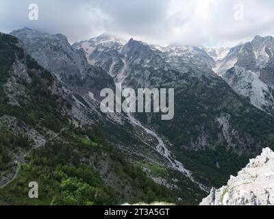 Panoramablick auf die Landschaft mit schneebedeckten Bergen, Wäldern, Tal und steinernen Flussbetten in den albanischen alpen Stockfoto