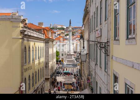 Lisboa, Portugal - 18.09.2023 Blick vom Bairro Alto auf eine typische Straße im Stadtzentrum von Lissabon mit der Säule von Pedro IV auf dem Rossio-Platz auf der Rückseite Stockfoto