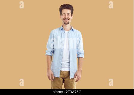Porträt eines attraktiven, lächelnden jungen Mannes mit Bart und Schnurrbart, gekleidet in weißem T-Shirt und blauem Hemd, der selbstbewusst direkt in die hineinblickt Stockfoto