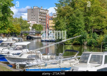 Blick vom Flussufer auf dem Quai de Versailles auf Yachten, Boote und Hausboote auf dem Erdre. Die Fußgängerbrücke verbindet die Insel L'Ile de Versailles. Stockfoto