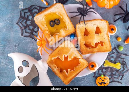 Lustige Kindergerichte zu Halloween, Snack- oder Brunch-Sandwiches mit geröstetem Brot, Käse in Form von traditionellen Halloween-Monstern - Kürbislaterne Stockfoto