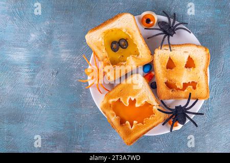 Lustige Kindergerichte zu Halloween, Snack- oder Brunch-Sandwiches mit geröstetem Brot, Käse in Form von traditionellen Halloween-Monstern - Kürbislaterne Stockfoto