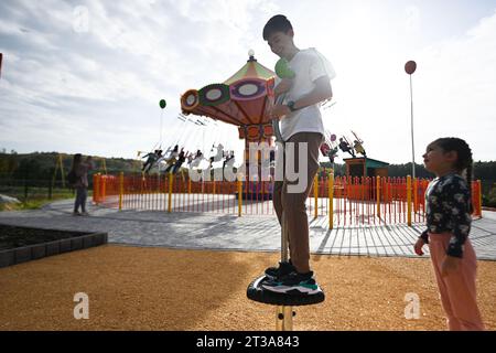 Kinder spielen auf einer Schaukel in einem Vergnügungspark. Sonnige Herbstzeit. Stockfoto