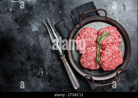 Rohe Frikadellen aus Hackfleisch, rohe Fleischkoteletts. Schwarzer Hintergrund. Draufsicht. Leerzeichen für Text Stockfoto