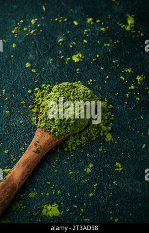 Nahaufnahme eines Holzlöffels mit etwas Matcha-Pudertee auf einer dunklen, strukturierten Steinoberfläche Stockfoto