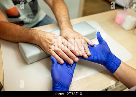 Männer Maniküre. Die Hände eines älteren Mannes werden vom Manikürspezialisten im Schönheitssalon gehalten. Blick von oben Stockfoto