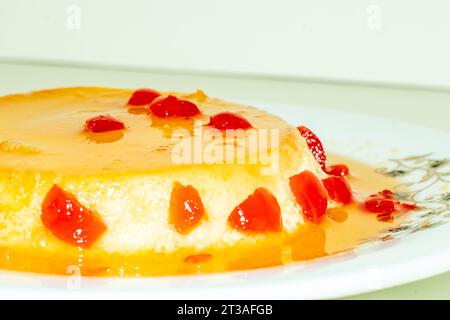 Der hausgemachte Pudding wird mit roten Kirschfrüchten belegt. Ein Pudding ist ein gekochtes süßes Essen, das aus Zutaten hergestellt wird Stockfoto