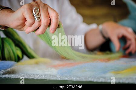 Filzkünstlerin Andrea Hunter in ihrem Studio in Wensleydale in den Yorkshire Dales, Großbritannien. Andrea wendet die Prinzipien des Zeichens und Malens auf die Verwendung feiner Schichten Merinowolle an, um subtile Töne und Farben in Landschaftsfilzen zu erzeugen. Stockfoto