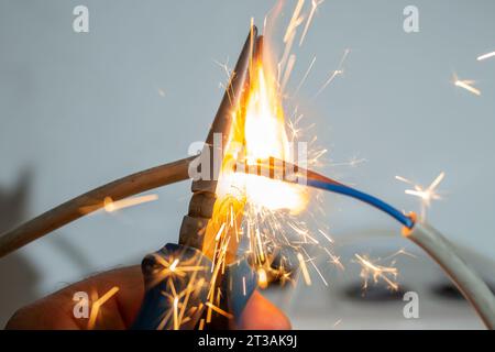 Flammen und Funken mit einer Zange, die elektrische Kabel schneidet, Brandschutzkonzept, Soft Focus Stockfoto