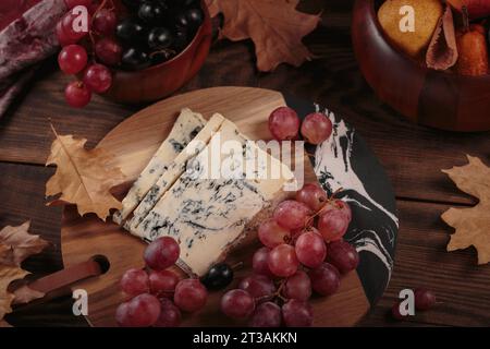 Käseplatte mit Herbstfrüchten und trockenen Blättern Stockfoto