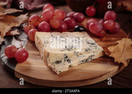 Käseplatte mit Herbstfrüchten und trockenen Blättern Stockfoto