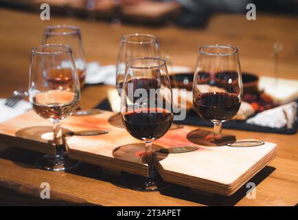 Abendessen, Weinprobe in einem alten Weingut. Elegante Weingläser, gefüllt mit roten, weißen und rosa Auswahl auf rustikalem Holztisch. Gäste genießen Gespräche Stockfoto