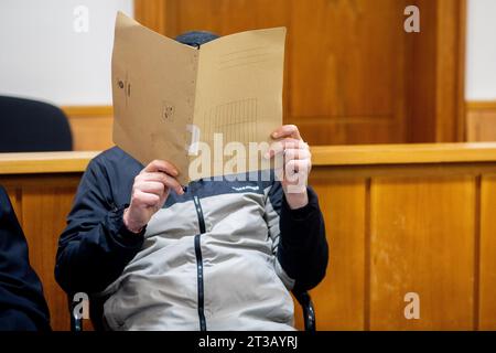 Oldenburg, Deutschland. Oktober 2023. Der Angeklagte sitzt vor Beginn des Prozesses in einem Gerichtssaal vor dem Bezirksgericht und hält einen Aktenschutz vor seinem Gesicht. Laut Ermittlungen soll der Mann im April 2023 einen weiteren Patienten in einer Klinik in Bad Zwischenahn mit massiver Gewalt gegen seinen Hals getötet haben. Während des Prozesses leugnete der Angeklagte das Verbrechen. Quelle: Hauke-Christian Dittrich/dpa/Alamy Live News Stockfoto