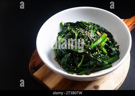 Food Concept Spot Focus koreanischer Spinatsalat auf schwarzem Hintergrund mit Kopierraum Stockfoto