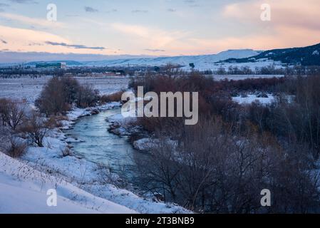 Wunderschöne Schneelandschaft nach einem Schneesturm mit einem Fluss und Bäumen ohne Blätter bei Sonnenuntergang im Winter, Torrejon de Ardoz, Madrid, Spanien Stockfoto