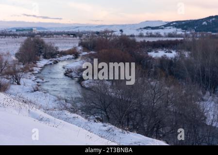 Wunderschöne Schneelandschaft nach einem Schneesturm mit einem Fluss und Bäumen ohne Blätter bei Sonnenuntergang - vorne im Fokus, Torrejon de Ardoz, Madrid, Spanien Stockfoto