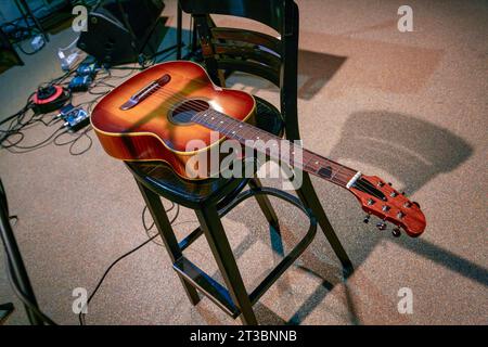 Bildmusikinstrument Akustikgitarre liegt auf einem Stuhl Stockfoto