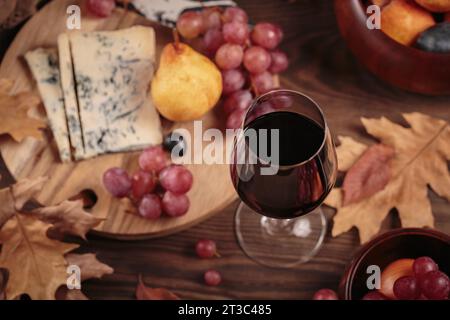 Herbstpicknick mit Wein- und Käseplatte, Früchten und trockenen Blättern Stockfoto