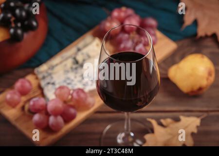 Herbstpicknick mit Wein- und Käseplatte, Früchten und trockenen Blättern Stockfoto