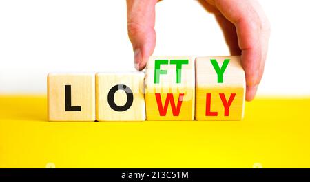 Symbol „hoch“ oder „niedrig“. Concept Words Lofty niedrig auf Holzblock. Schöner gelber Tisch mit weißem Hintergrund. Geschäftsmann Hand. Geschäftlich hoch oder niedrig c Stockfoto