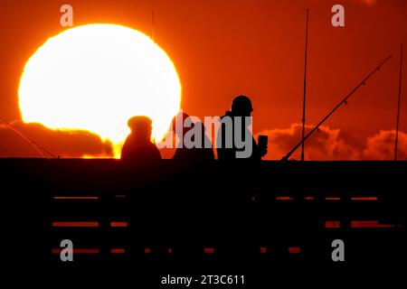 Isle Of Palms, Usa. Oktober 2023. Fischer, die von Sonnenaufgang umgeben sind, warten am Isle of Palms Pier am 24. Oktober 2023 in Isle of Palms, South Carolina, auf die Fische. Quelle: Richard Ellis/Richard Ellis/Alamy Live News Stockfoto