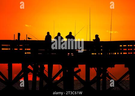 Isle Of Palms, Usa. Oktober 2023. Fischer, die von Sonnenaufgang umgeben sind, warten am Isle of Palms Pier am 24. Oktober 2023 in Isle of Palms, South Carolina, auf die Fische. Quelle: Richard Ellis/Richard Ellis/Alamy Live News Stockfoto