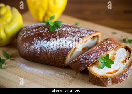 Gekochter süßer Kuchen mit Quitte und Kürbis innen, Hefeteig-Rolle, auf einem Holztisch. Stockfoto