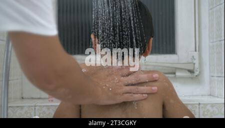 Waschen Sie den Rücken Ihres Kindes in Super-Ultra-Zeitlupe. Moms Hand streichelt die Kinderhaut sanft und badet ihren Jungen Stockfoto