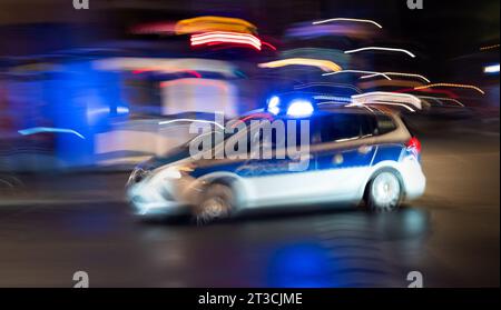 Oktober 2023, Berlin: 01.10.2023, Berlin. Ein Polizeiauto fährt nach Einbruch der Dunkelheit mit blauen Lichtern auf einer Straße der Hauptstadt. (Foto mit gezogener Kamera und längerer Belichtungszeit). Foto: Wolfram Steinberg/dpa Foto: Wolfram Steinberg/dpa Stockfoto