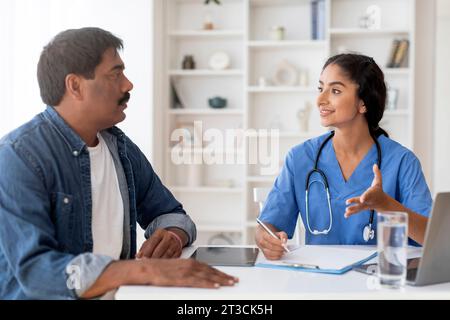 Lächelnde Indische Ärztin Spricht Mit Männlichem Patienten Während Eines Arzttermins Stockfoto